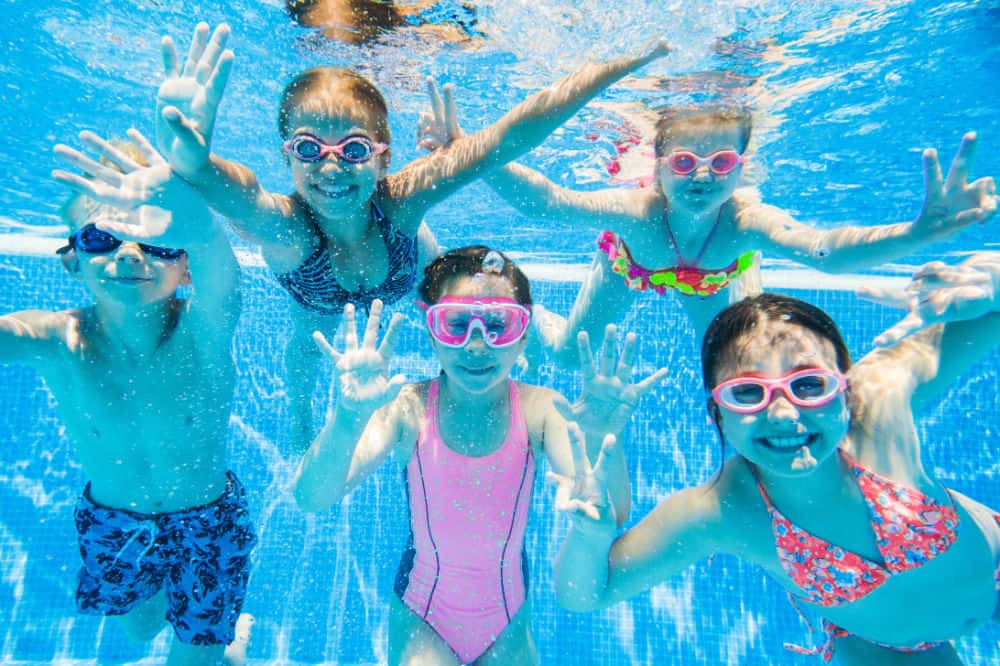 Kids swimming underwater in a clear pool