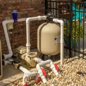 Sand filter and pump with red-handled valves on an equipment pad