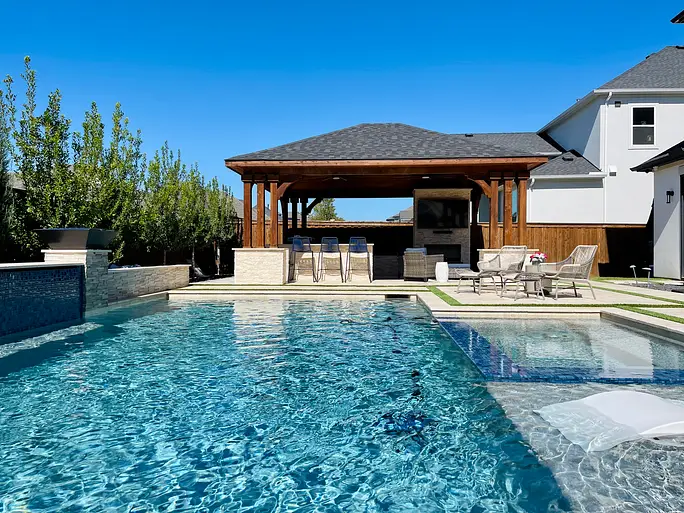 Clean backyard pool with a covered patio and outdoor kitchen in North Texas
