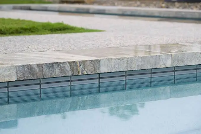 Pool tile ideas for North Texas- gray porcelain waterline tile under travertine coping Pool tile ideas: blue-gray waterline tile under stone coping